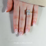 Hand wearing a diamond ring with 'single outline french' nail design on a neutral background