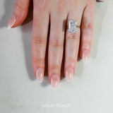 Hand wearing a diamond ring with 'micro french' text on a neutral background