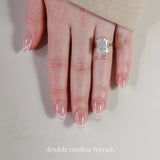 Hand wearing a diamond ring with 'double outline french' nail design on a neutral background