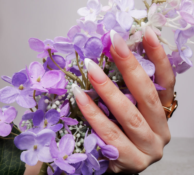 Reusable nail extensions in long almond length French nails. 