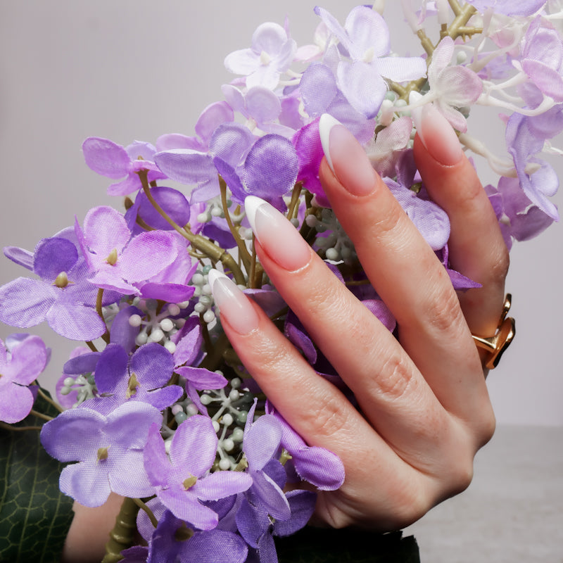 Reusable nail extensions in long almond length French nails. 