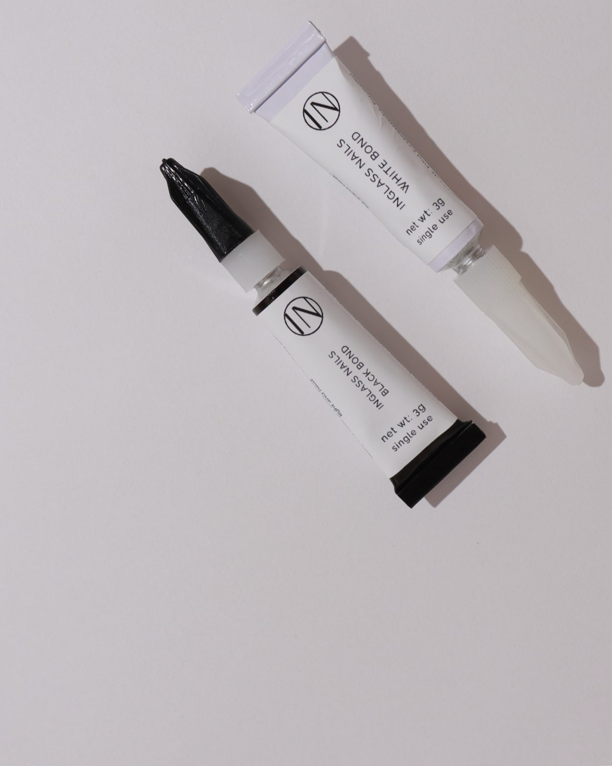 Two bonder bottles with black caps on a light gray background