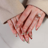 Close-up of hands with floral nail design wearing a beige coat.
