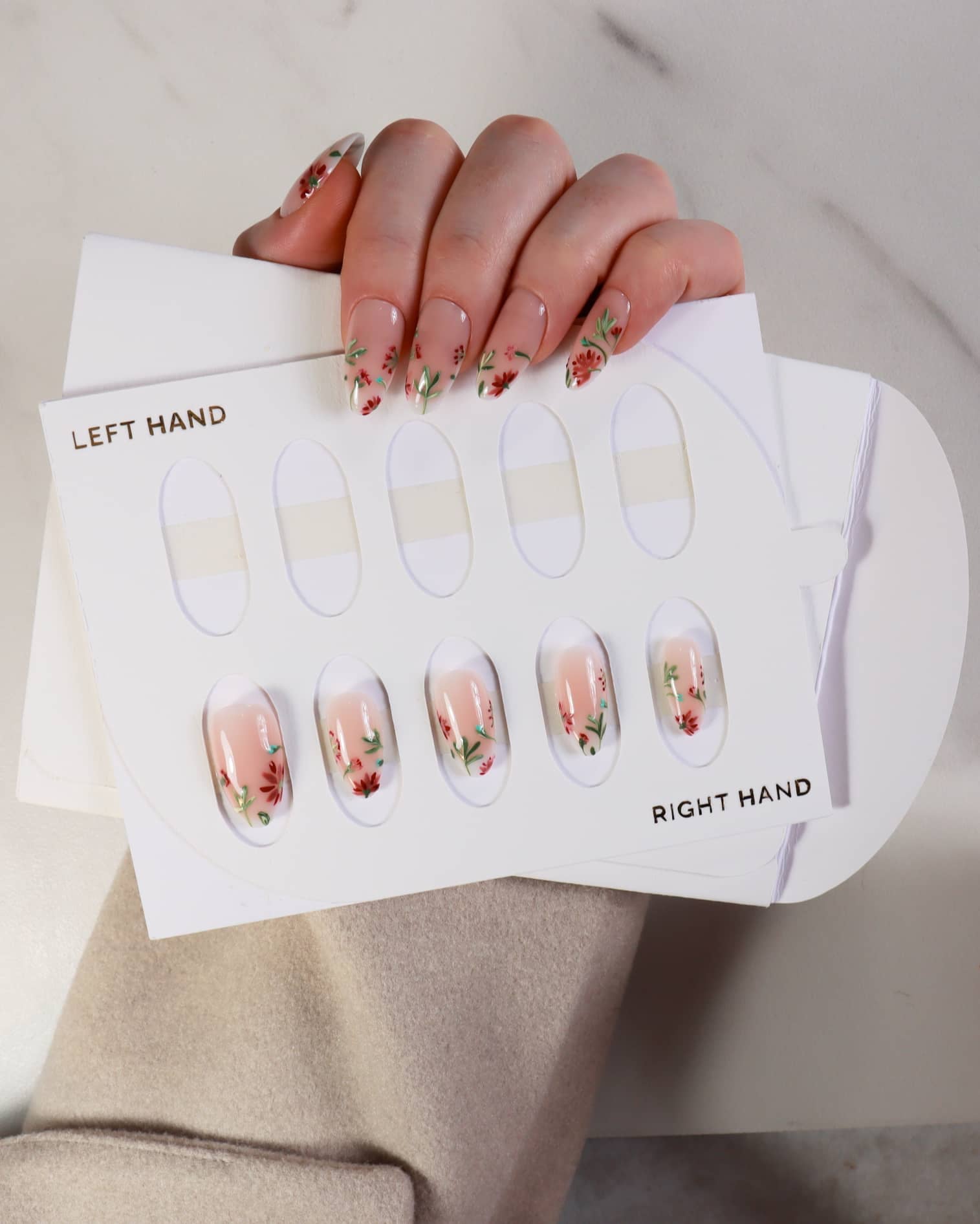 Nail art design sheet with floral patterns held by a hand