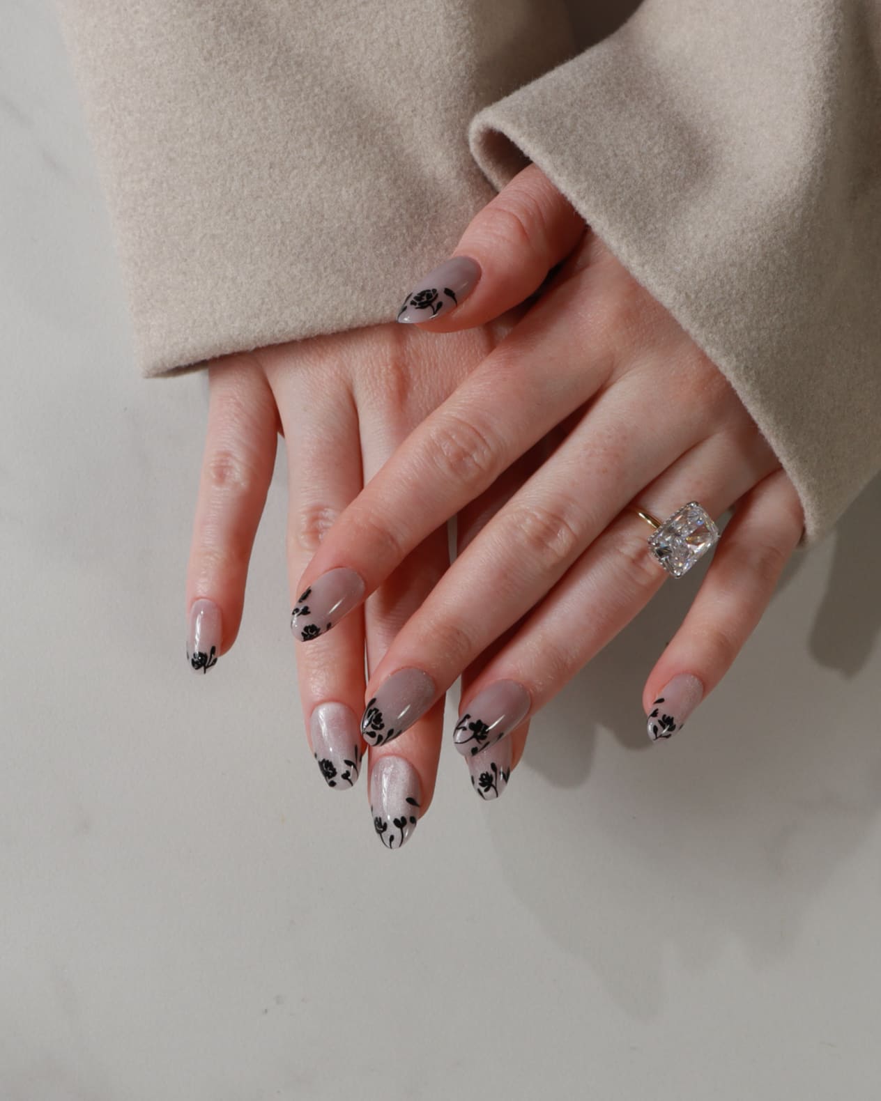 Close-up of hands with decorative nail art on a neutral background