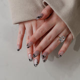 Close-up of hands with decorative nail art on a neutral background