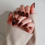 Close-up of a hand with dark nail polish wearing a beige sleeve against a neutral background