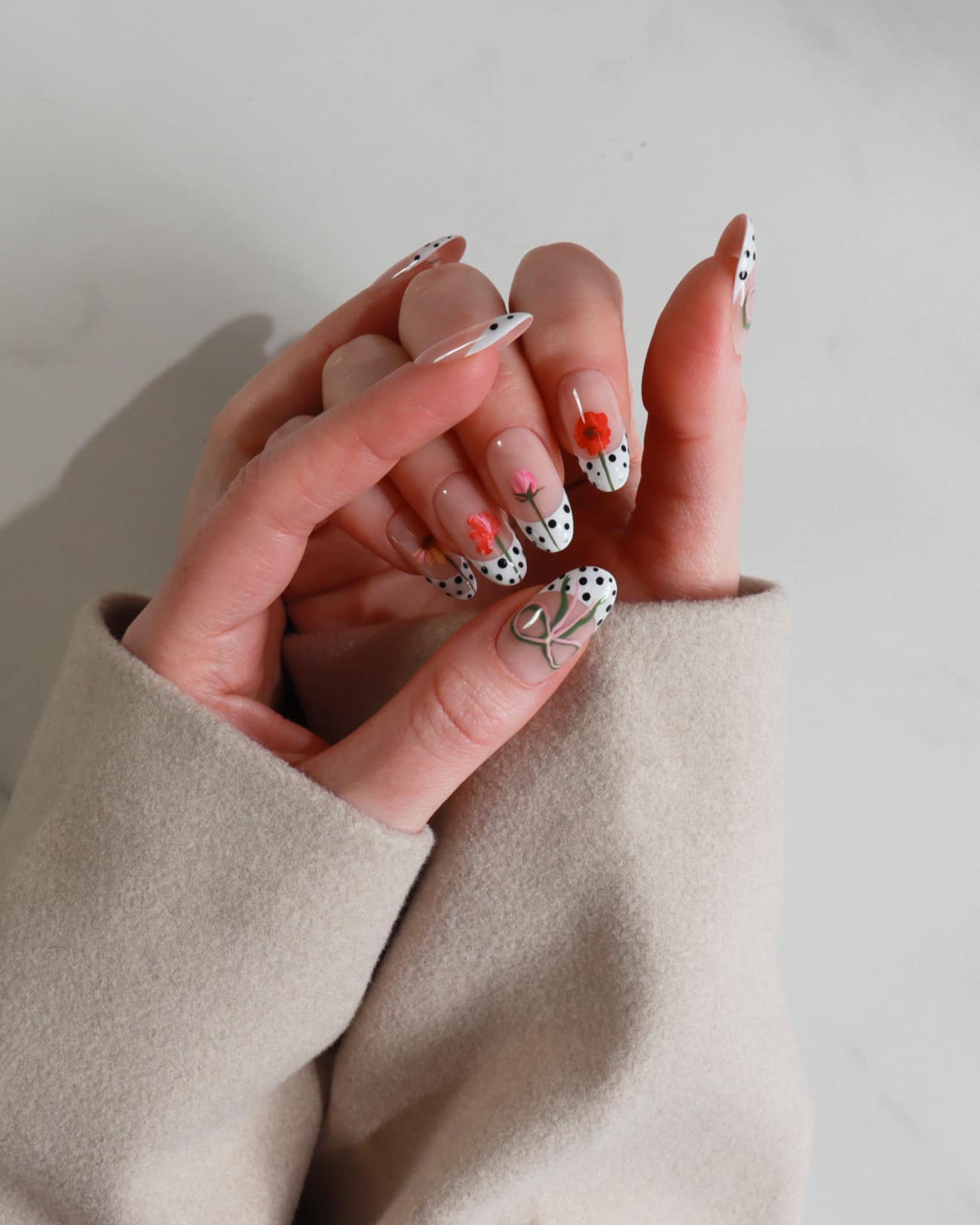 Hand with intricately designed nails held against a neutral background