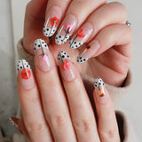 Close-up of hands with decorative nail art featuring polka dots and flowers.