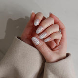 Close-up of hands with glittery gel polish against a neutral background