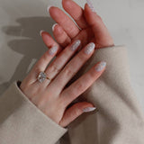 Hand with glittery gel polish wearing a ring on a neutral background
