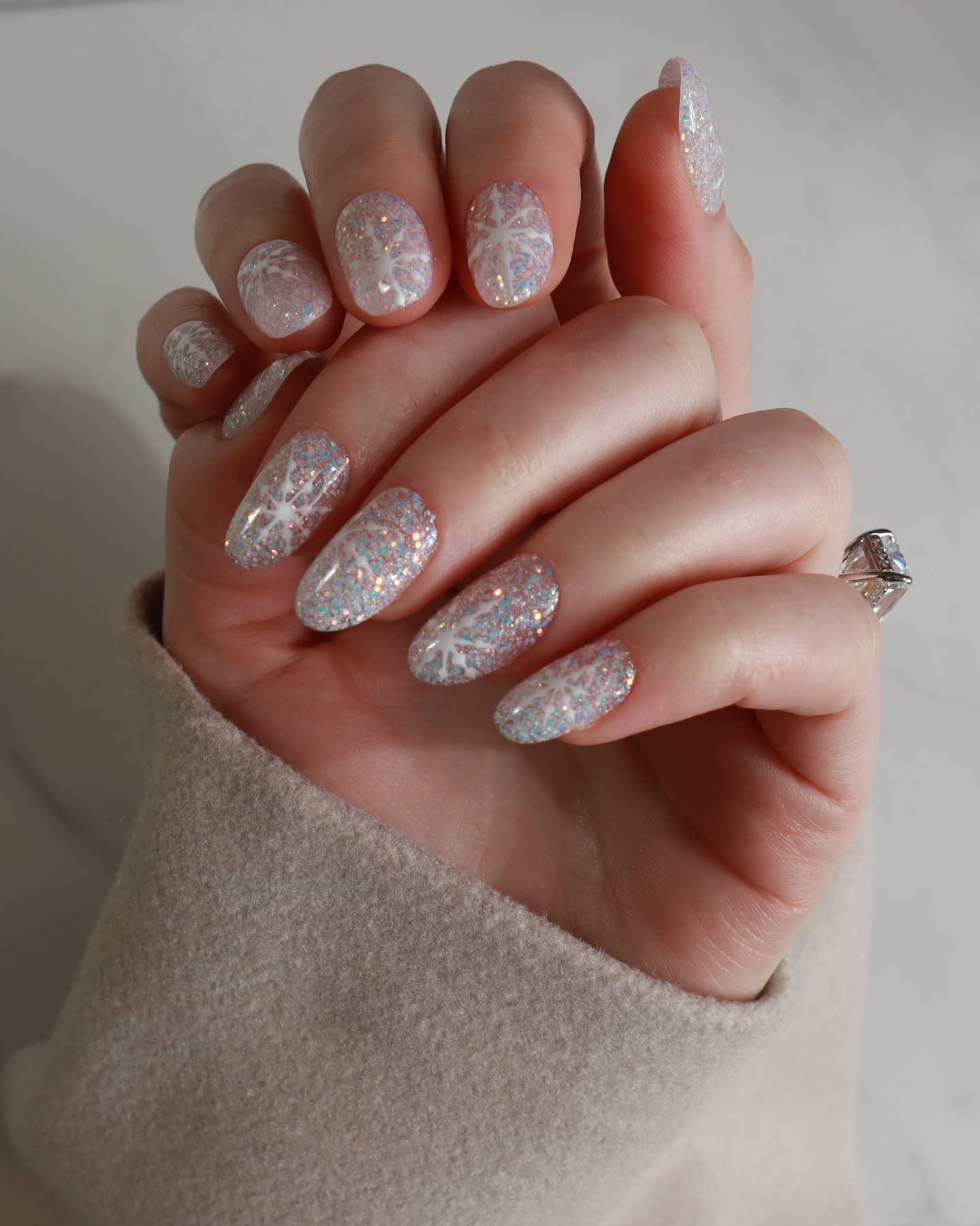 Hand with glittery gel polish on a neutral background