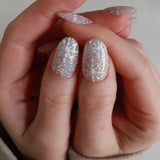 Close-up of a hand with glittery gel polish on a neutral background