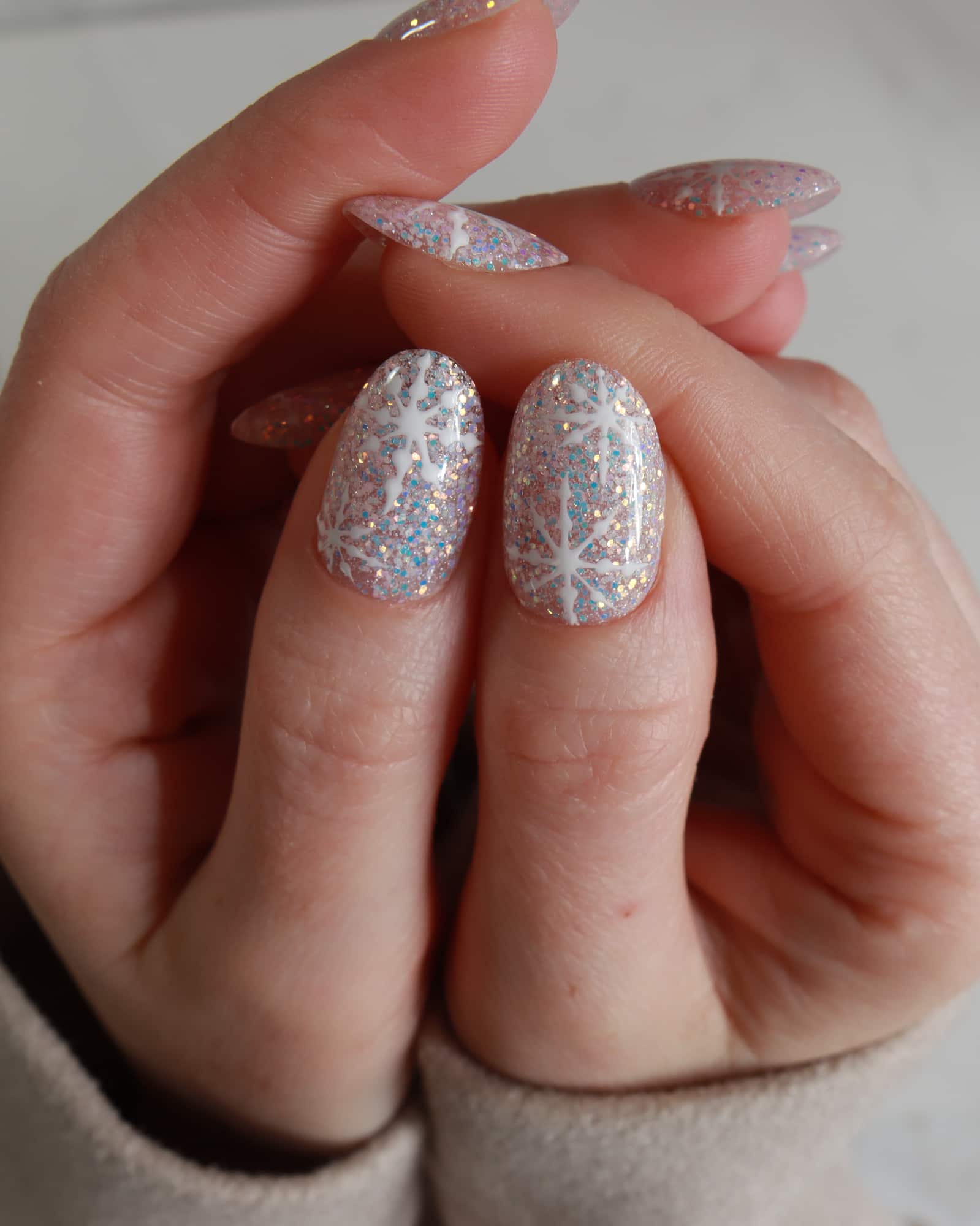 Close-up of a hand with glittery gel polish on a neutral background