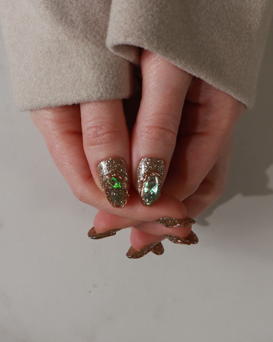 Close-up of a hand with glittery polish on a neutral background