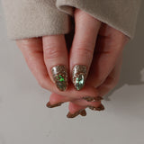 Close-up of a hand with glittery polish on a neutral background