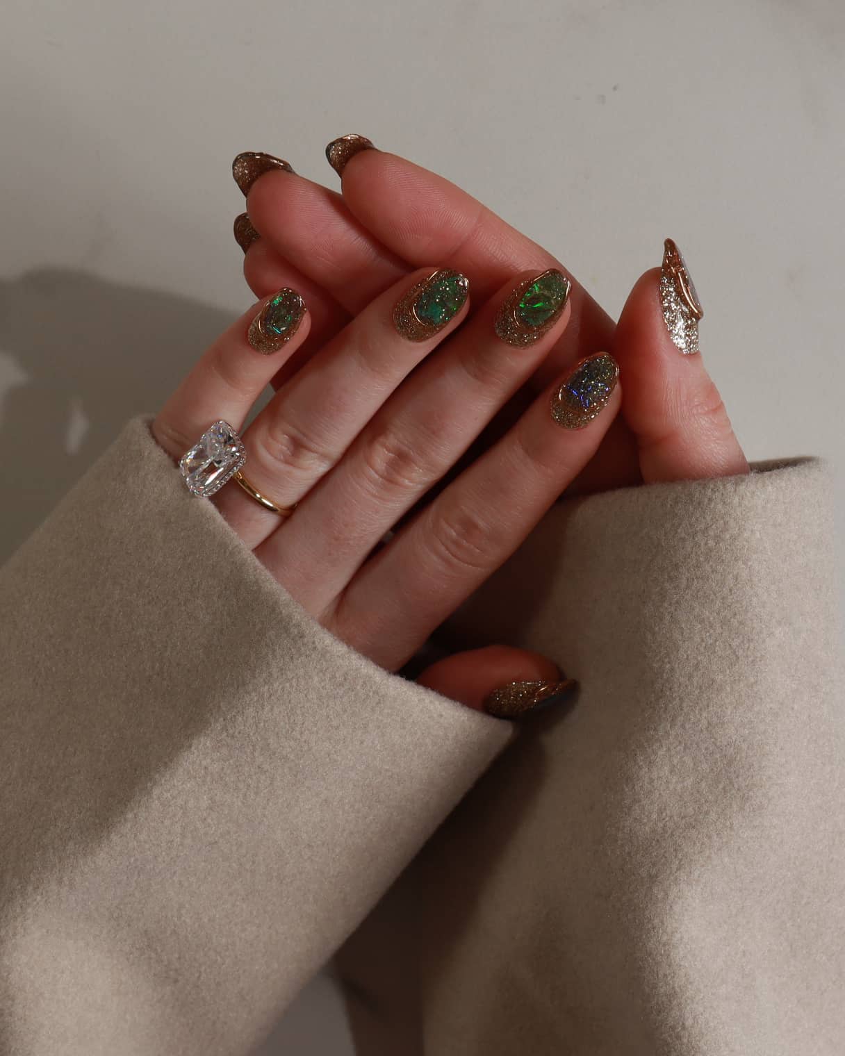 Hand with maximalist nail art against a neutral background