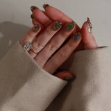 Hand with maximalist nail art against a neutral background