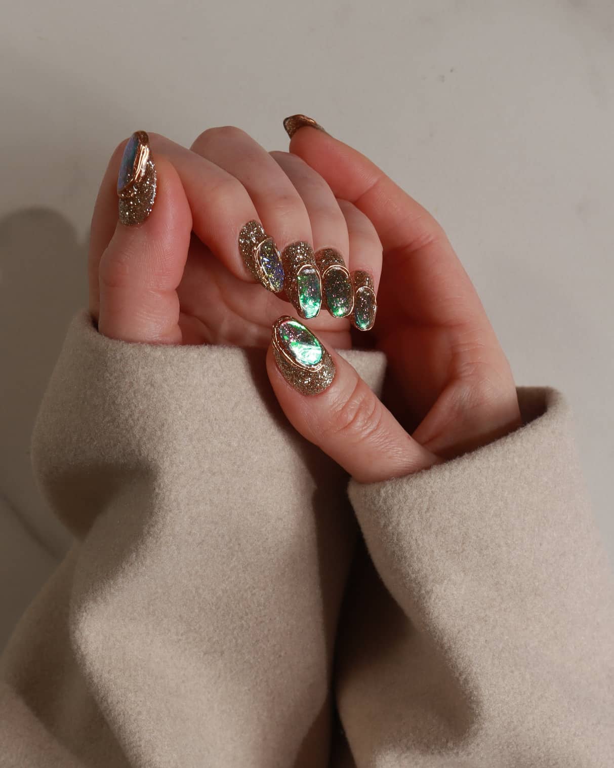 Close-up of a hand with decorative nail art wearing a beige sweater.