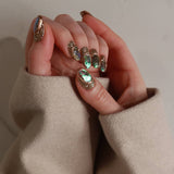 Close-up of a hand with decorative nail art wearing a beige sweater.