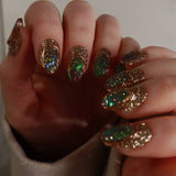 Close-up of a hand with glittery green and gold polish.