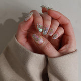 Close-up of a hand with glittery nail polish wearing a beige sleeve.