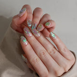 Hand with glittery nail polish on a neutral background