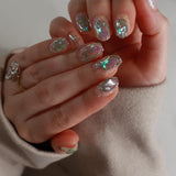 Close-up of a hand with decorative nail art and rings on a neutral background