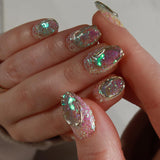 Close-up of a hand with glittery, multicolored nail polish on a neutral background