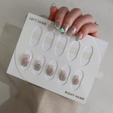 Set of false nails with glittery designs on a display card, held by a hand.