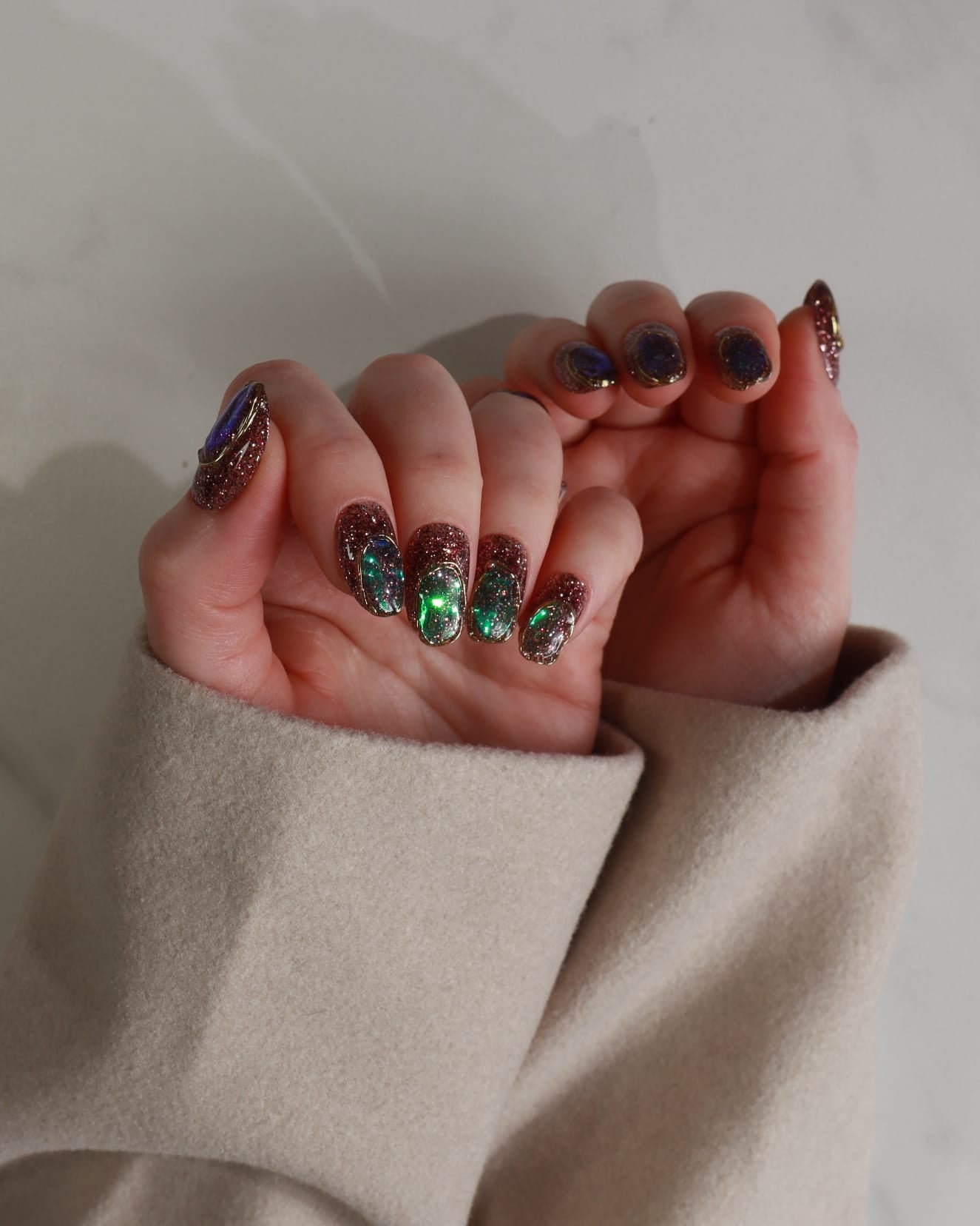 Close-up of hands with decorative nail art against a neutral background