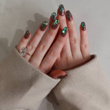 Close-up of hands with decorative nail art and a ring, wearing a beige sleeve.