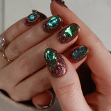 Hand with glittery, multicolored nail polish on a neutral background