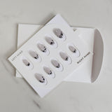 Set of false nails in a packaging box on a light gray background