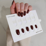 Nail polish samples on a card held by a hand with dark nail polish.