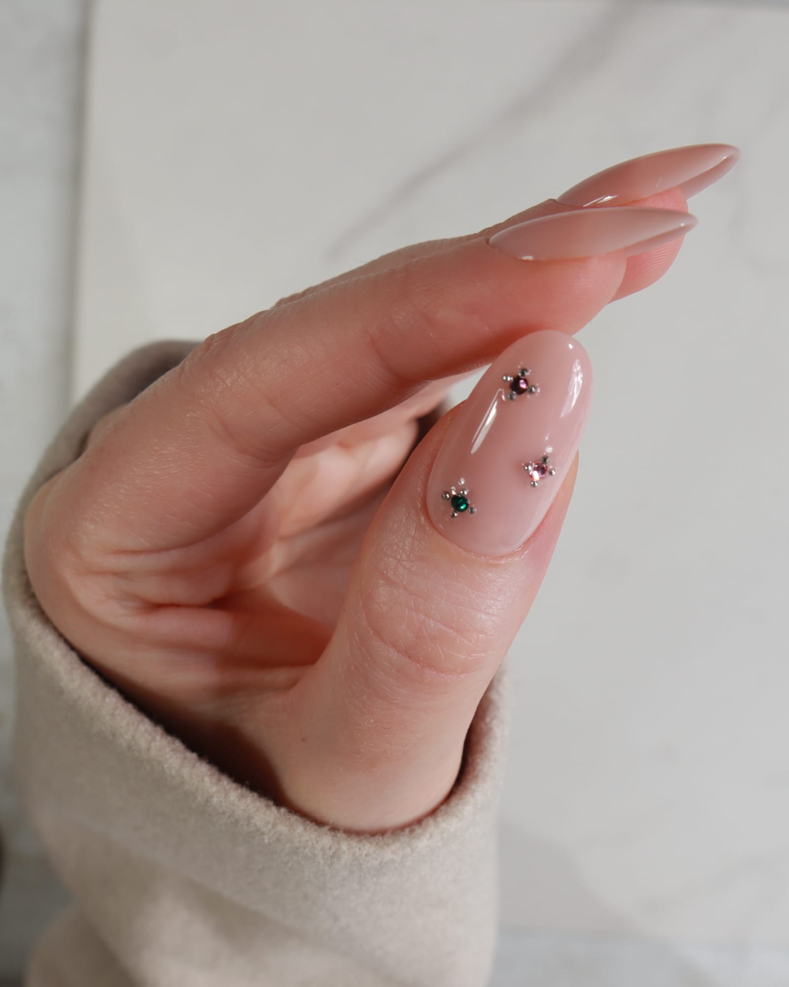 Close-up of a hand with decorative nails on a plain background