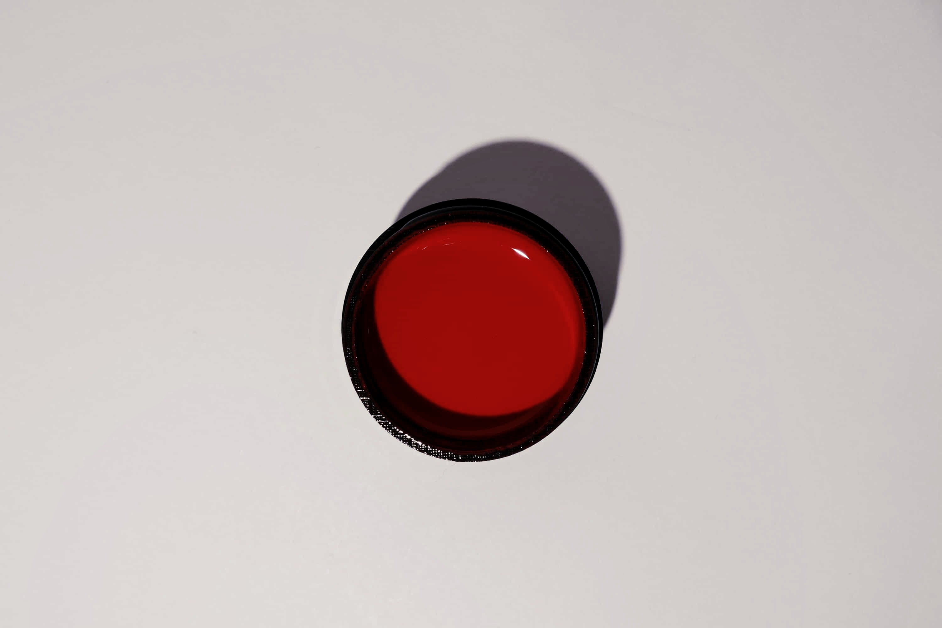 Red circular object with black rim on a white background