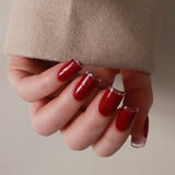 Hand with red nail polish wearing a beige coat