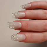 Hand with clear nail polish and embedded pearls on a neutral background