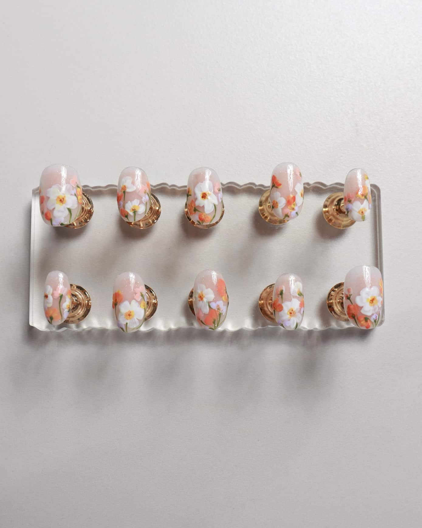 Set of nail art samples on a display board with a floral design.