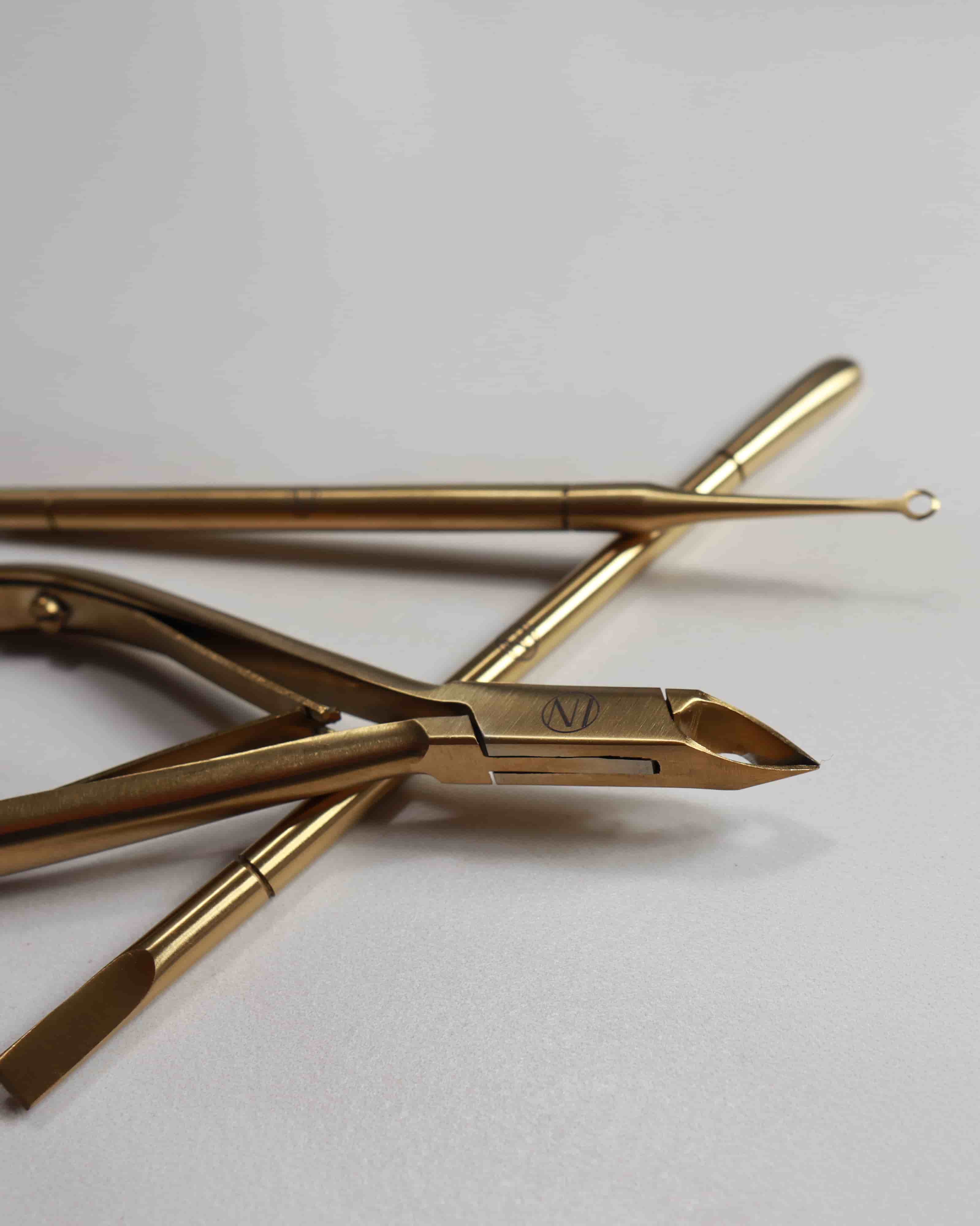 Gold-colored nail tools on a white background