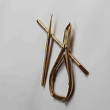 Gold-colored nail tool on a light gray background