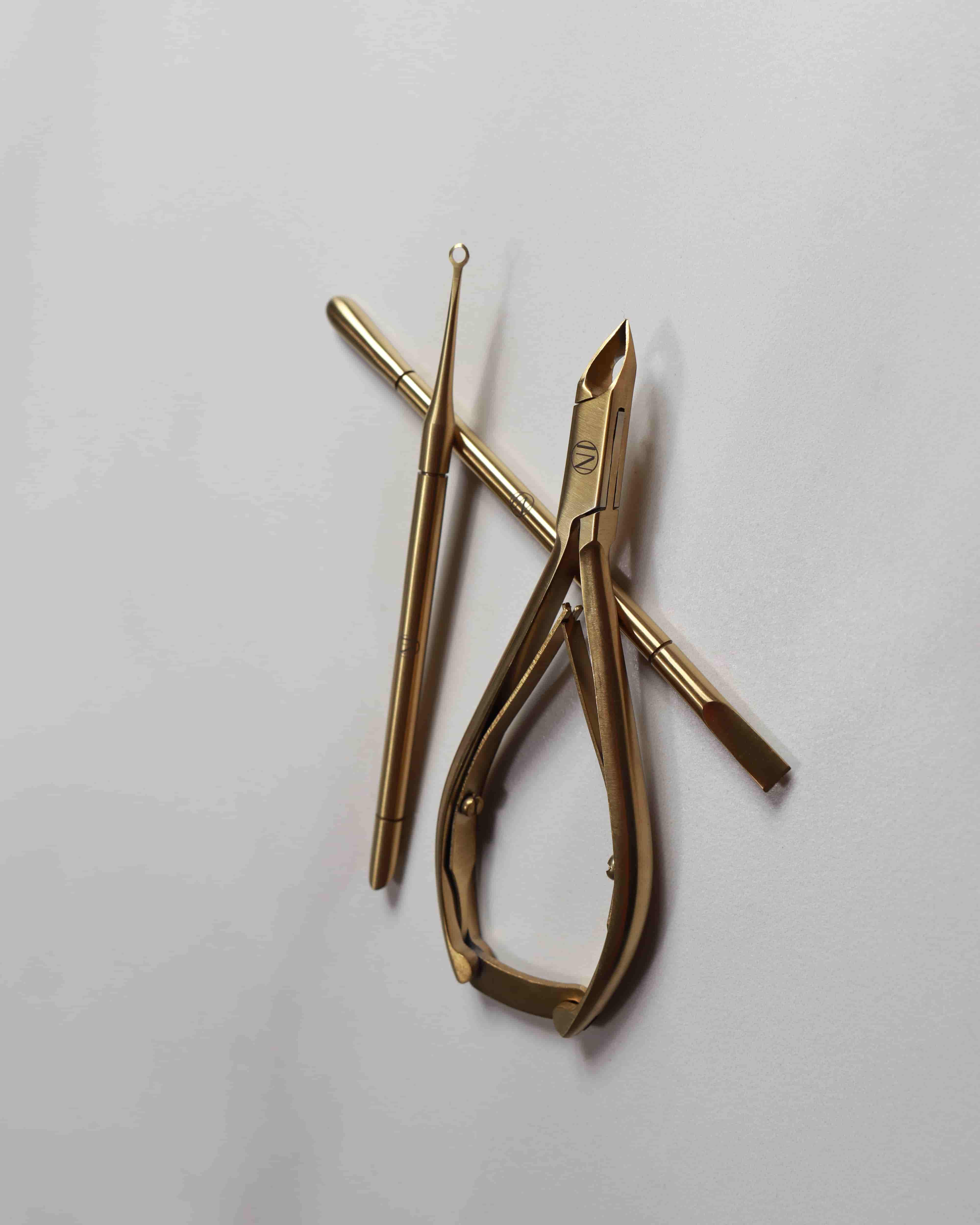Gold-colored nail tool on a light gray background