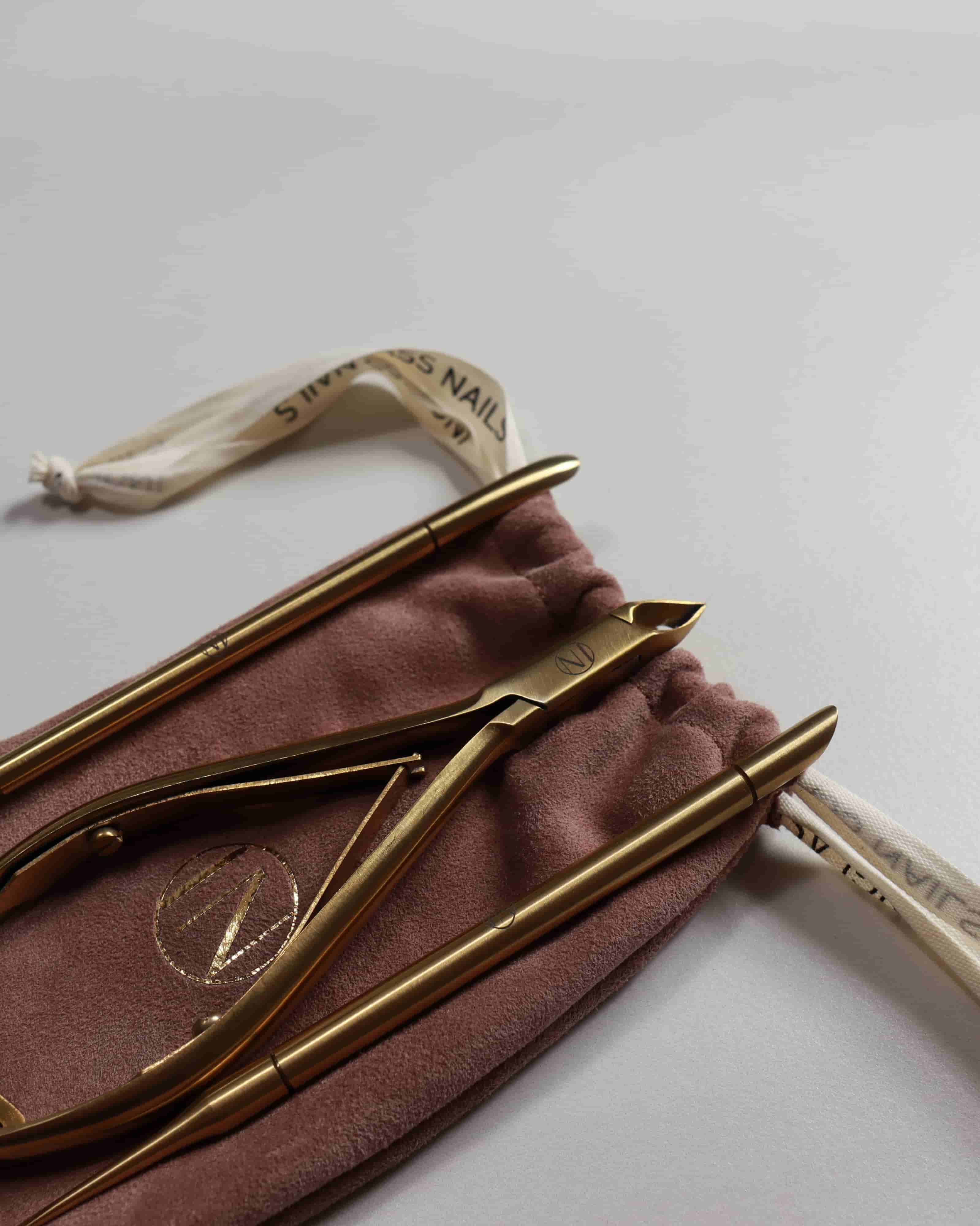 Set of gold-colored nail tools on a brown cloth with a visible brand logo.