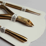 Three gold nail tools on a white card with visible branding.
