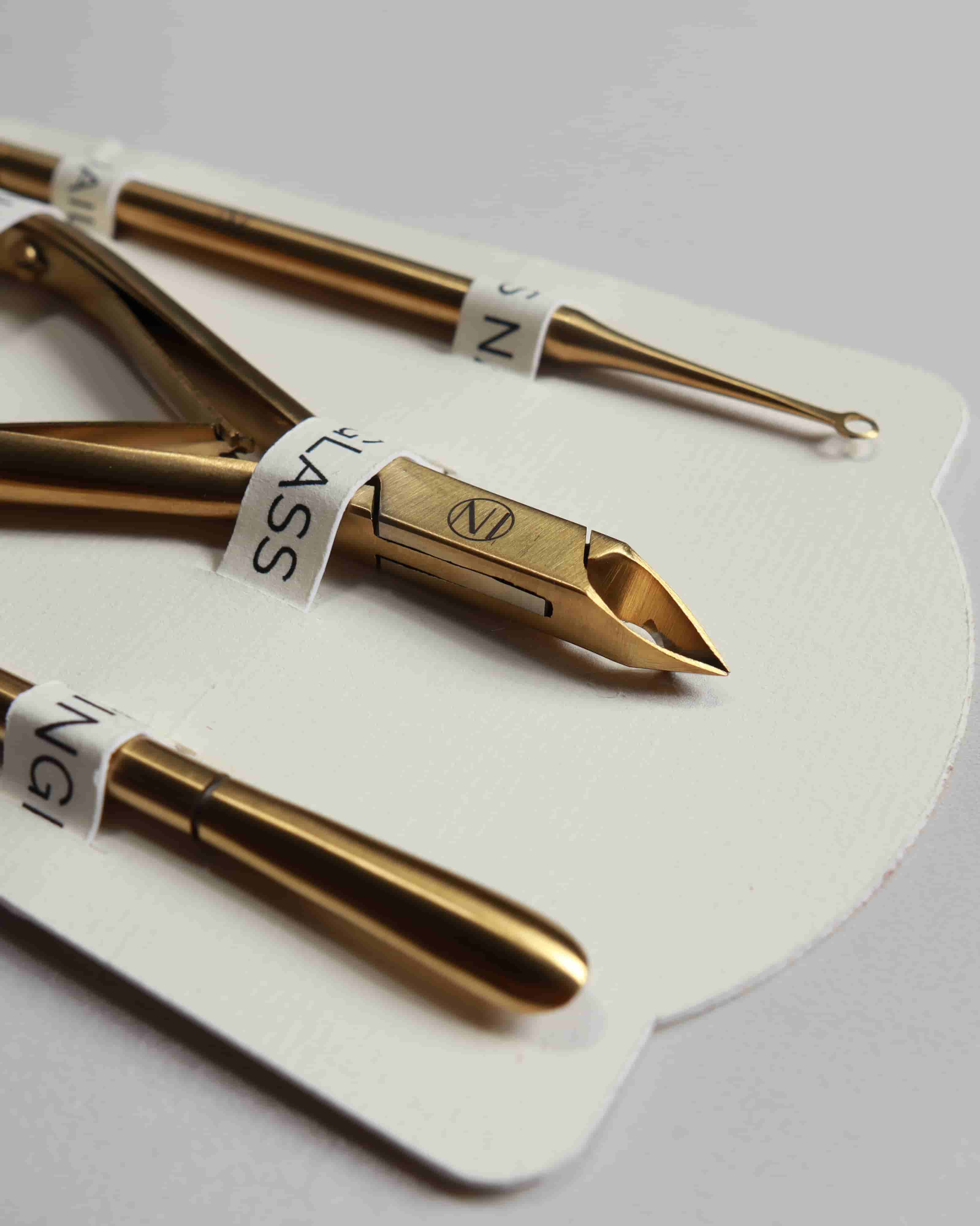Three gold nail tools on a white card with visible branding.