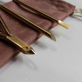Gold nail tools on a brown cloth with a white background