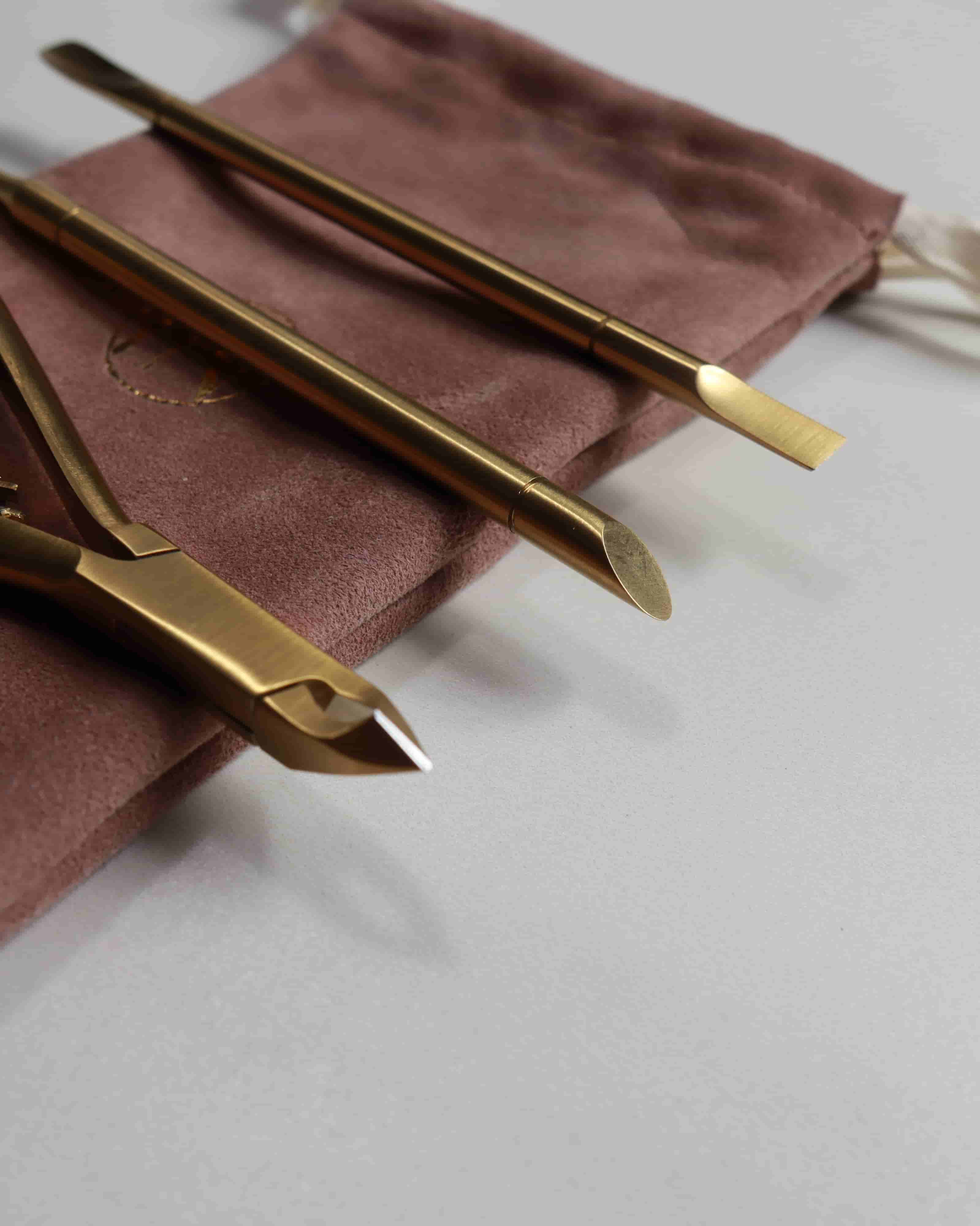 Gold nail tools on a brown cloth with a white background