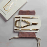 Set of gold nail tools with a branded box on a gray surface