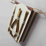 Set of gold nail tools in a white case on a light gray background